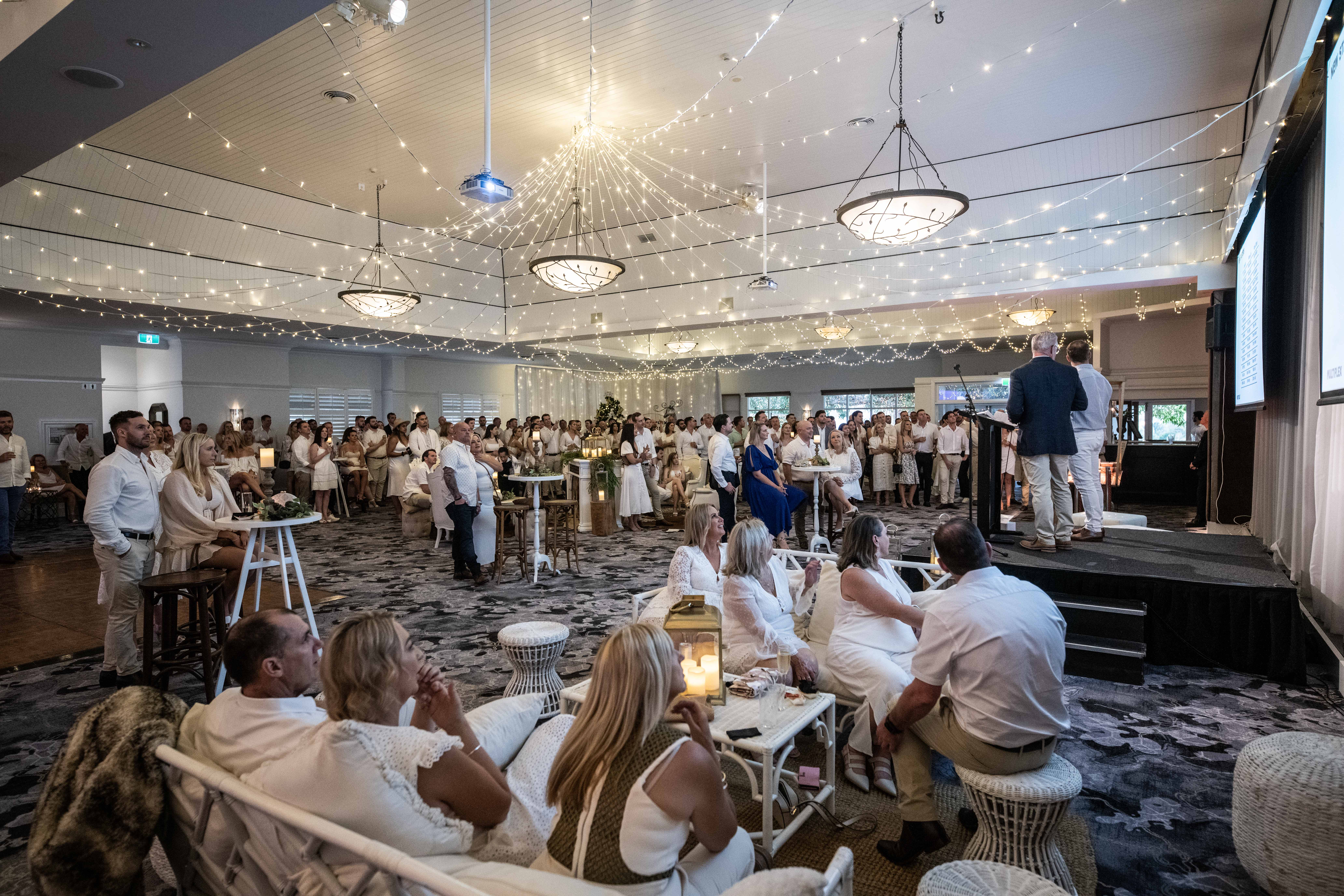 Corporate gathering with guests and speaker on stage inside the a large event venue in Brisbane