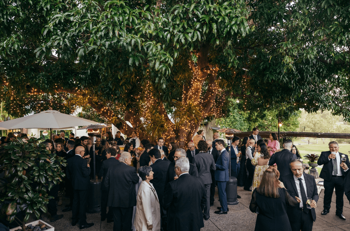 Guests gathered under the mango tree with fairy lights at a private gathering in Brisbane at Hillstone St Lucia